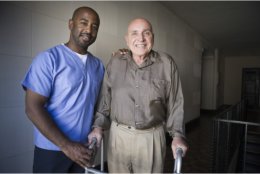 Caregiver assisting old man to walk